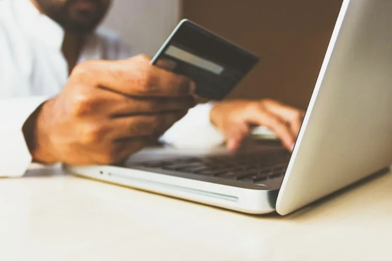 Person holding a credit card at a laptop